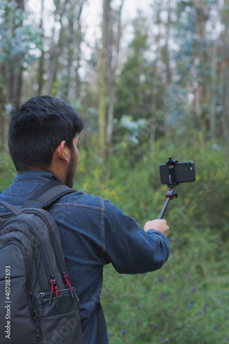 Young man walking in the woods taking selfies.