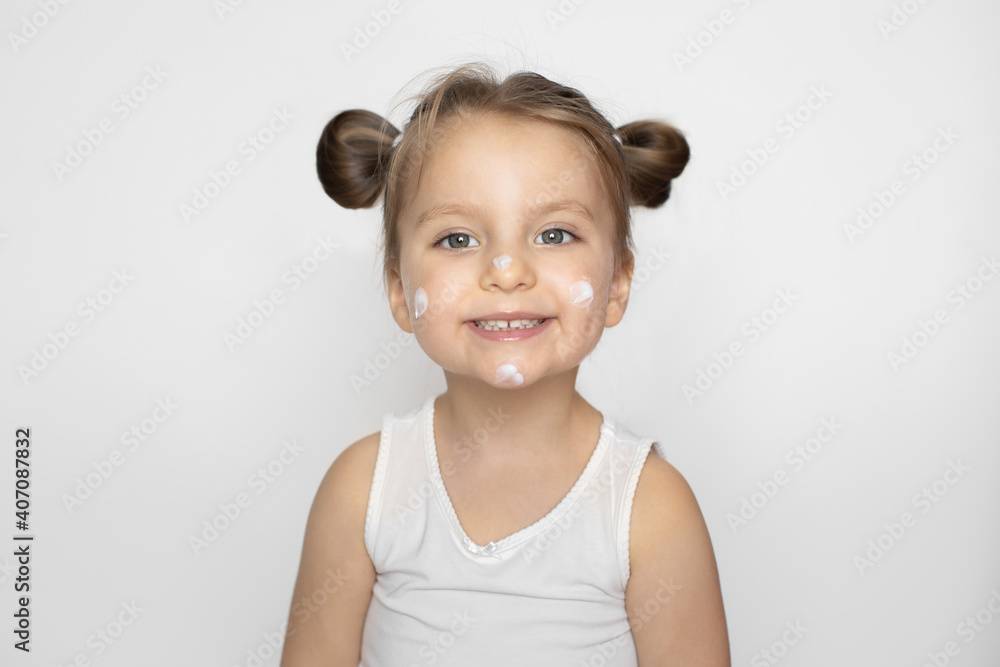 Kid cosmetics, face cream, skin care concept. Adorable smiling little girl with cream on her face, copying mom behavior, using cosmetics. Isolated on white, copy space Kid cosmetics, face cream, skin care concept. Adorable smiling little girl with cream on her face, copying mom behavior, using cosmetics. Isolated on white, copy space