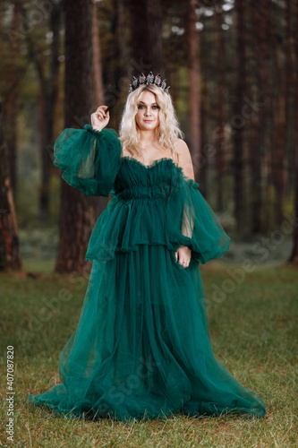 young beautiful blonde hair woman queen. Princess walks. autumn green forest mystic. Vintage medieval shiny crown. Long evening green dress. magic fantasy