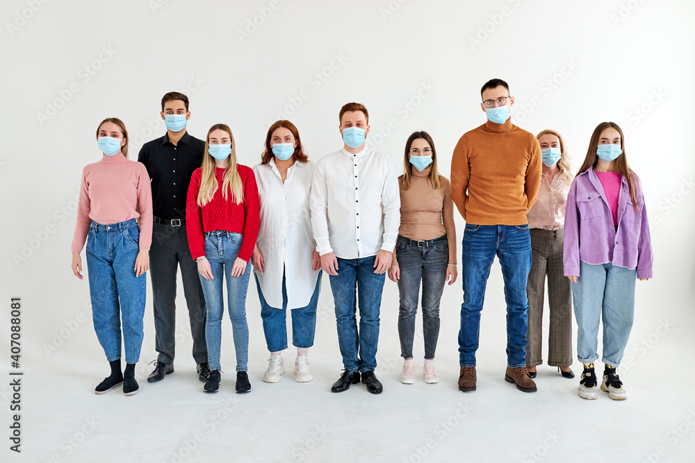 Obraz premium group of people in medical face masks during Covid second wave outbreak confidently posing at camera. new normal lifestyle concept with young people isolated in studio, portrait