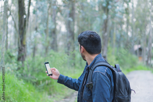 Young man walking in the woods taking selfies.