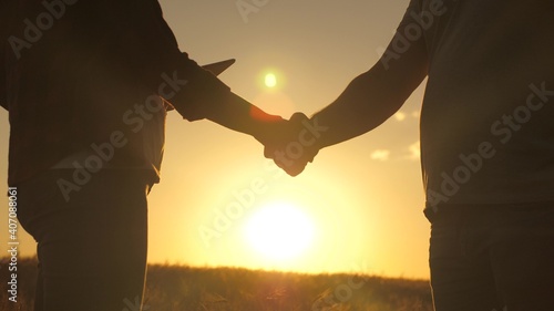 Business people shake hands in a wheat field in the sun. Business, teamwork. A male farmer extends his hand to female farmer. Handshake, joint work of farmers. The conclusion of the deal, agreed.