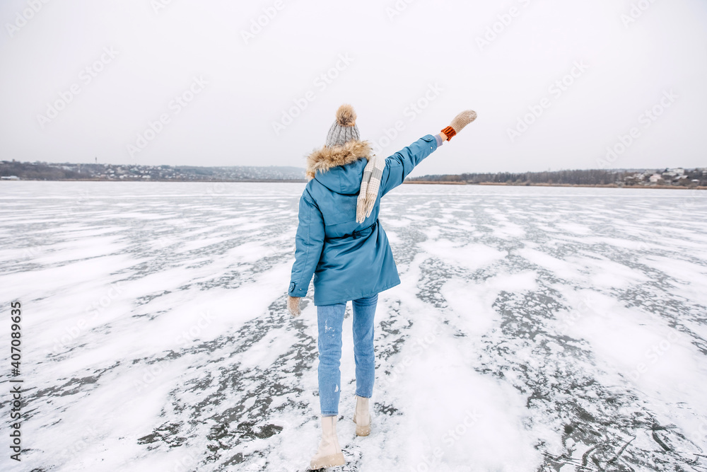 Woman walking on a frozen lake on a cold winter day.