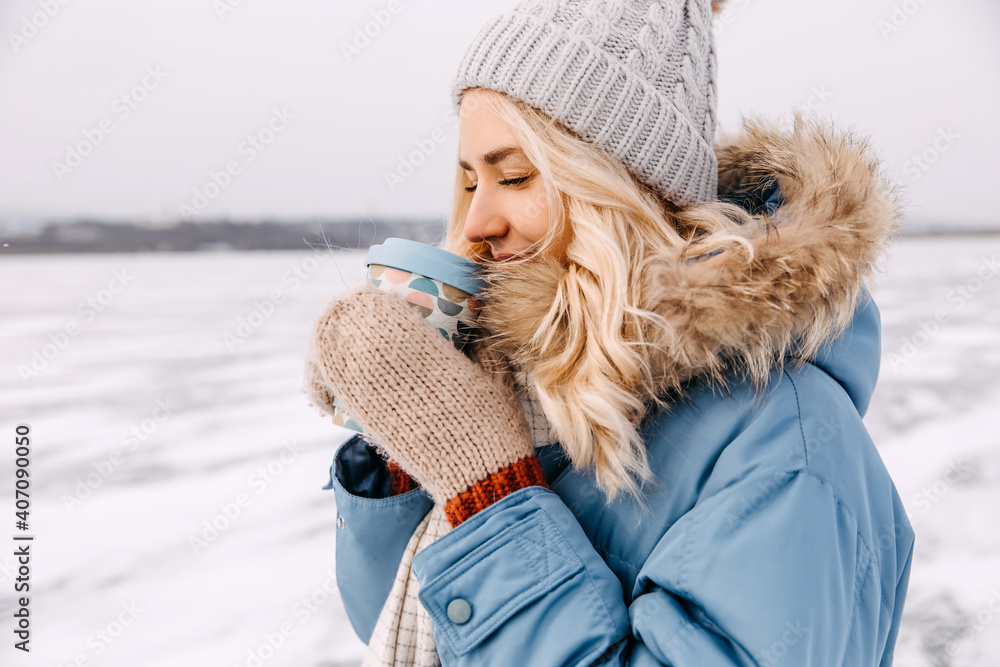 Closeup of a young blonde woman enjoying a cup of coffee on winter day, outdoors. Closeup of a young blonde woman enjoying a cup of coffee on winter day, outdoors.