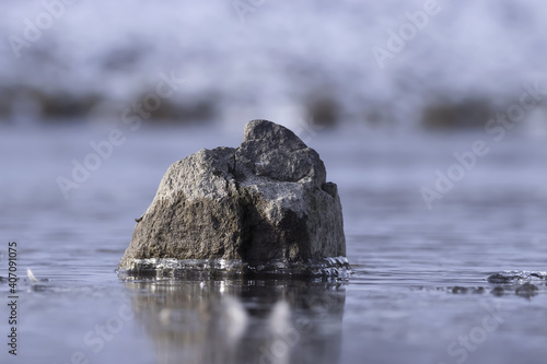 Stone lying in a frozen river. background ,texture, material