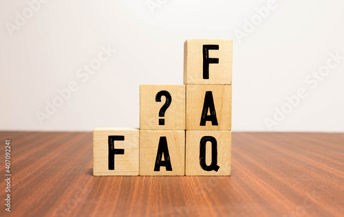 FAQ word on wooden block on top of wooden background.