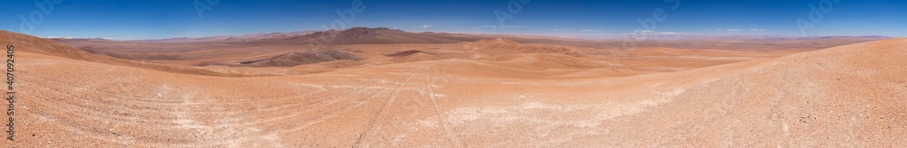Naklejka premium Atacama Desert arid landscape view. Dry mountains with sandstone and no life around us just rocks and sand. A lonely feeling on this amazing and wild scenery at a remote place