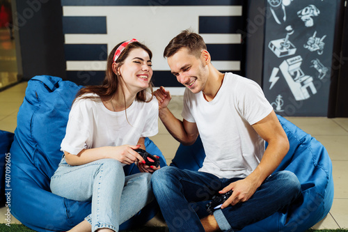 Front view. Friendly atmosphere during the playstation competition. Young lovers resting in a game club. Hold joysticks in hands, spending free time with laughter and pleasure. Playing computer games