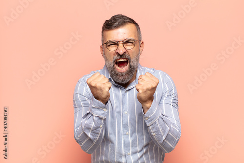 adult handsome man shouting aggressively with annoyed, frustrated, angry look and tight fists, feeling furious photo