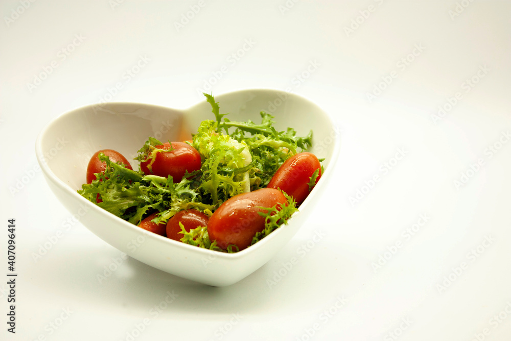 Mix of lettuce, carrots and red cherry tomatoes served in a ceramic heart shaped bowl Mix of lettuce, carrots and red cherry tomatoes served in a ceramic heart shaped bowl