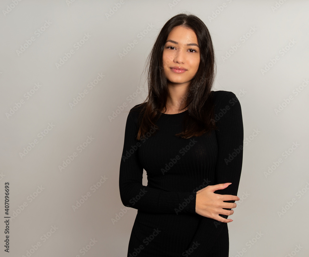 Beautiful young woman with long black hair posing in dress on grey ...