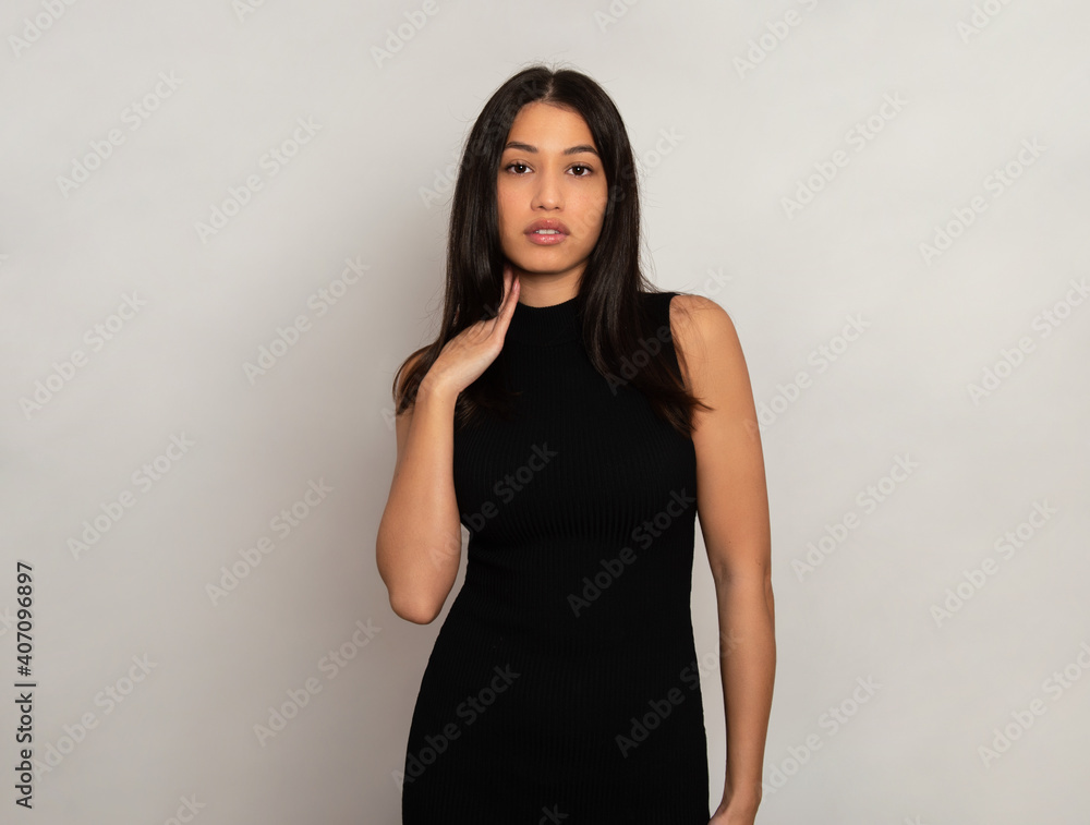 Beautiful young woman with long black hair posing in dress on grey background Beautiful young woman with long black hair posing in dress on grey background