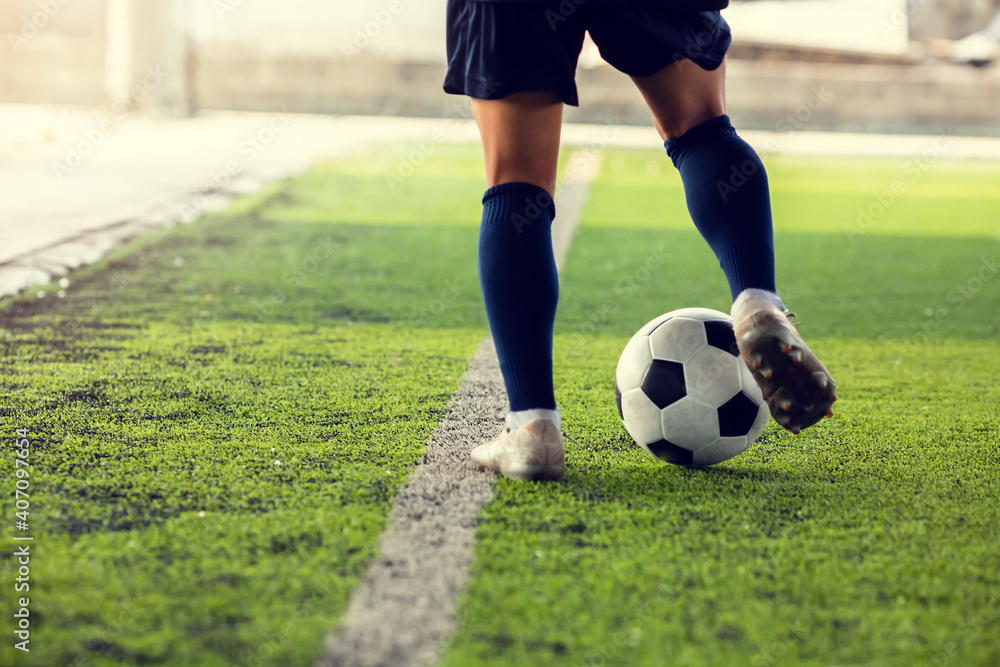 Selective focus to soccer ball with blur the footballer's feet are  jogging and controlling it on the artificial turf.