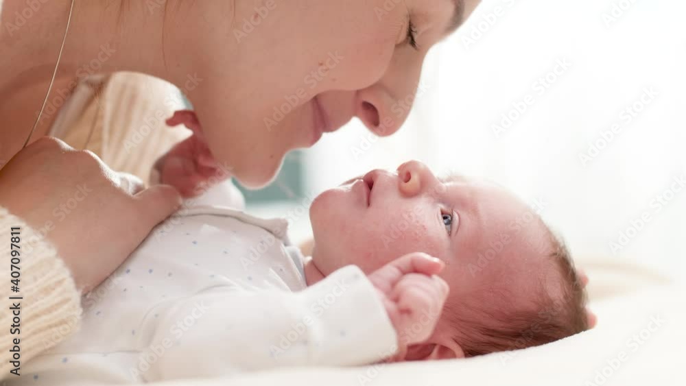 Closeup shot of beautiful young mother cuddling and stroking her little baby son lying on bed in sun light. Concept of family happiness and loving parents with little children Closeup shot of beautiful young mother cuddling and stroking her little baby son lying on bed in sun light. Concept of family happiness and loving parents with little children