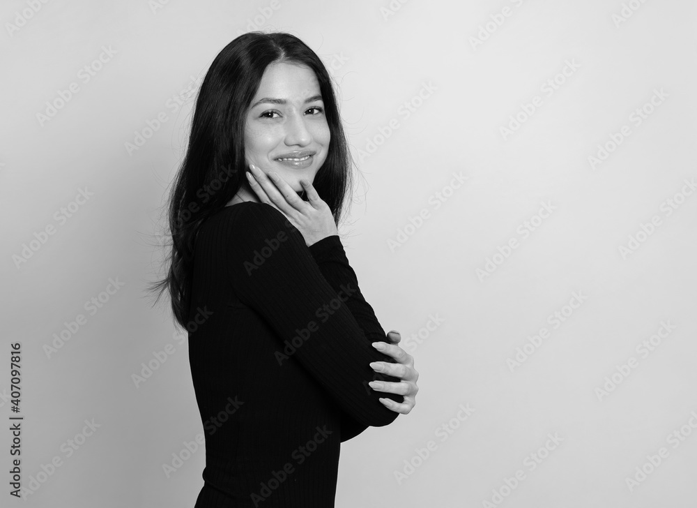 Beautiful young woman with long black hair posing in dress on grey background Beautiful young woman with long black hair posing in dress on grey background
