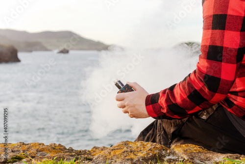 Unrecognizable person vaping with his electronic cigarette. Cloud of vapor from an e-cigar. photo