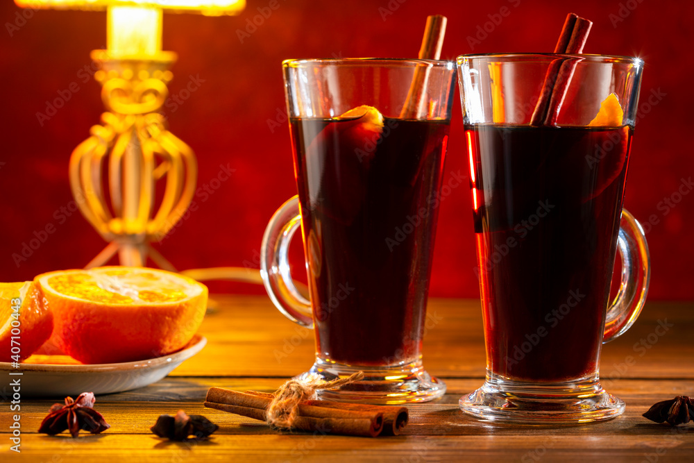 Mulled wine for two. Mulled wine in glass with cinnamon, spices and orange on wooden table. Mulled wine for two. Mulled wine in glass with cinnamon, spices and orange on wooden table.
