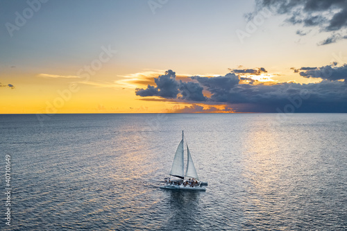 Aerial view of catamaran boat full of people sailing under an orange sunset, La Altagracia, Dominican Republic photo
