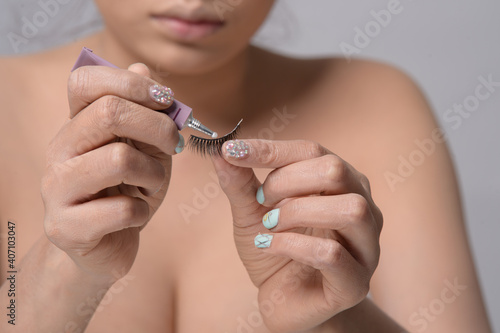 Closeup beautiful young asian woman with eyelash and a cosmetic glue extensions on white background. Closeup of  female model face with professional facial makeup.