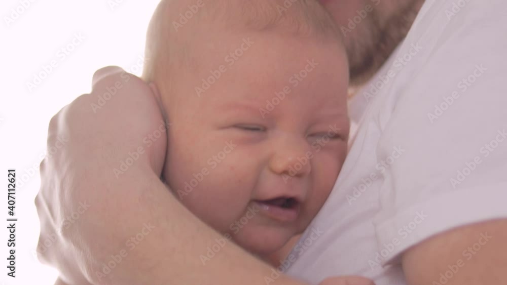 Close-up of a crying baby's face as the father tries to console his child. Close-up of a crying baby's face as the father tries to console his child.