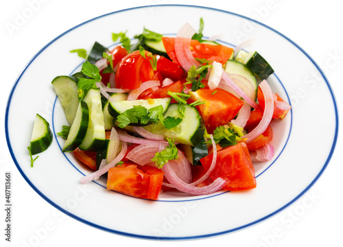 Traditional summer salad from fresh ripe tomatoes with cucumbers, red onion and parsley dressed with oil. Isolated over white background