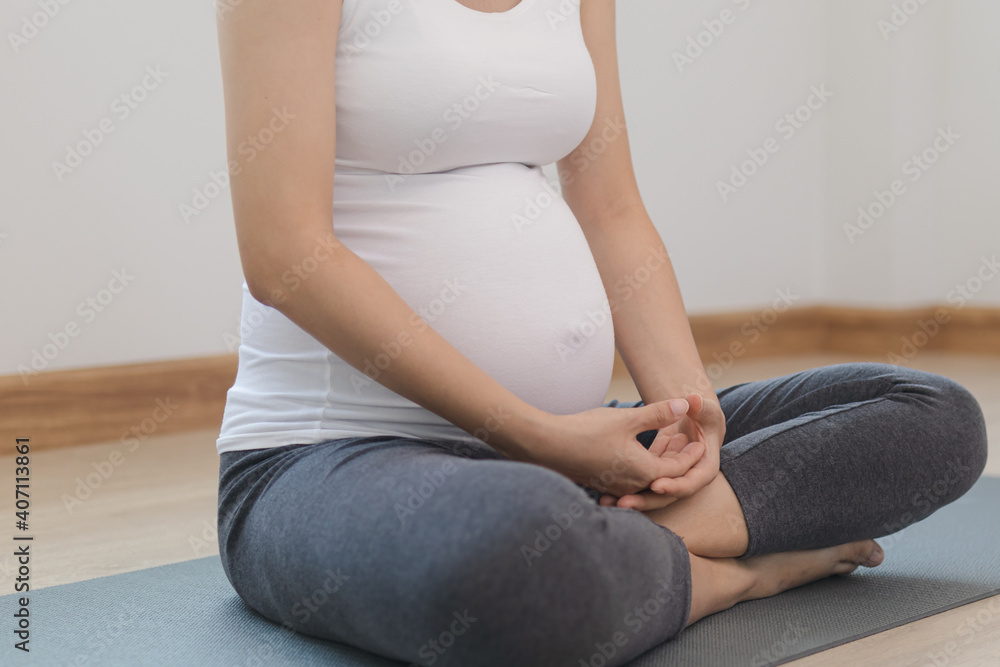 Calm pose young asian pregnant woman practice yoga for pregnant to meditation and exercise on mat for wellbeing while rest at home. Calm pose young asian pregnant woman practice yoga for pregnant to meditation and exercise on mat for wellbeing while rest at home.