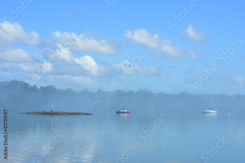 Hazy morning in calm harbour. Sky reflection on calm surface gives blue look to whole image.