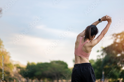 Young adult female in pink sportswear stretching muscle in the park outdoor, sport woman warm up ready for running and jogging in morning. wellness, fitness, exercise and work life balance concepts