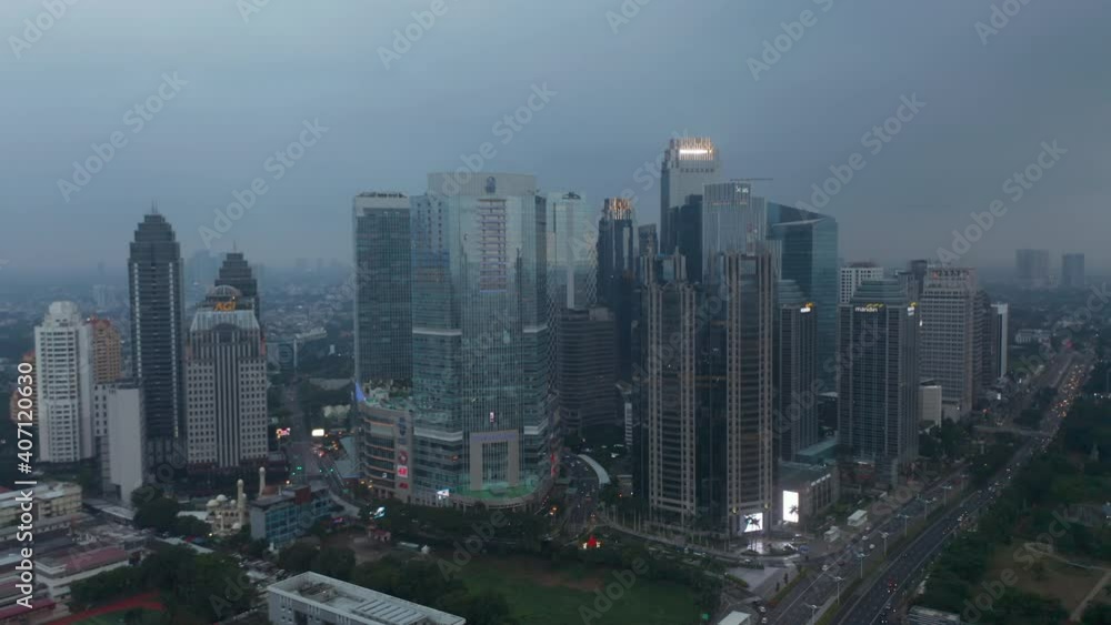 Aerial truck view circling around a building complex of multiple skyscrapers in modern city center by a motorway in Jakarta Aerial truck view circling around a building complex of multiple skyscrapers in modern city center by a motorway in Jakarta