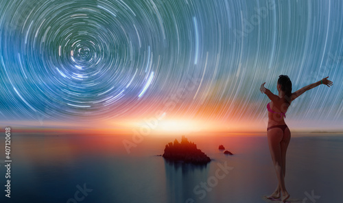 Long exposure image of Dramatic sky and seascape with Star trails at the beach - Happy slim girl in red and black bikini with raised up arms on the seashore in Alanya  Turkey