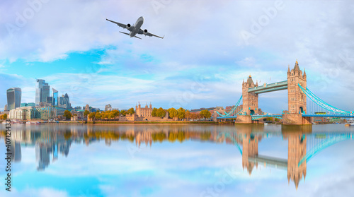 White airplane flying over London - Panorama of the Tower Bridge, Tower of London and modern skyline on Thames river - London, United Kingdom