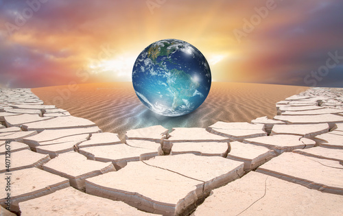 Climate change concept with earth planet on sand dune and dry soil 