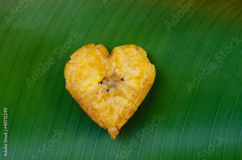 Heart shaped fried plantain isolated on a green leaf photo