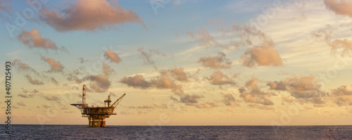 panorama view at sea during sunset with small oil platform at horizon