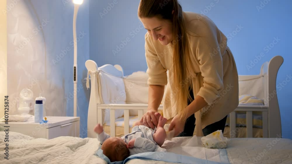 Stockvideo Smiling young mother changing diapers and wiping her newborn