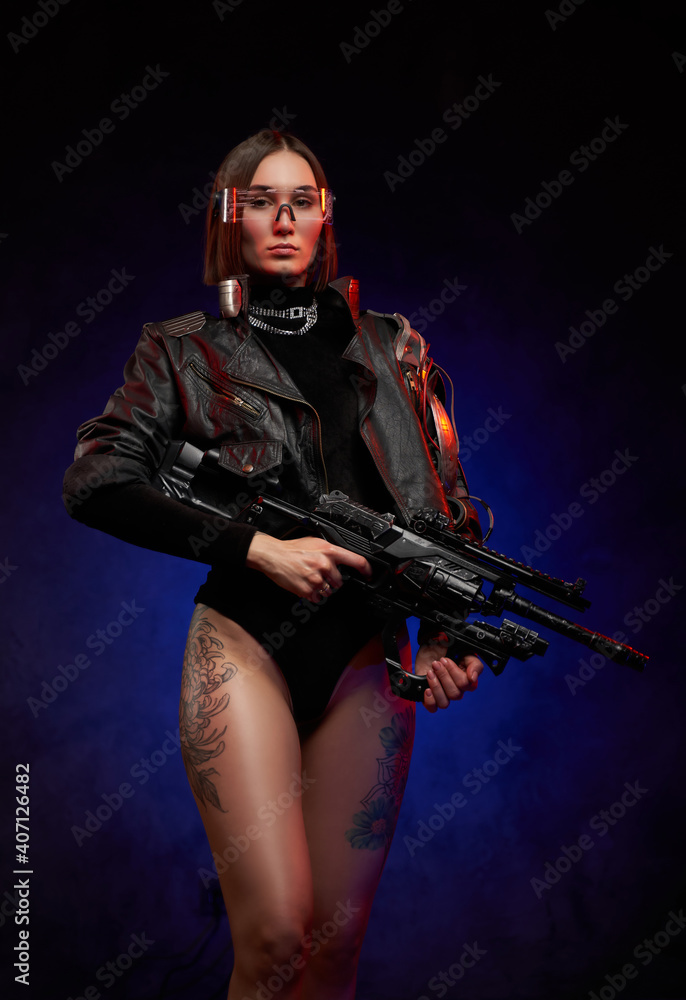 Martial and futuristic woman with implant and glasses posing in studio. Portrait of a attractive and sexy female soldier in black clothing with glasses and tattooed nude legs in dark background. Martial and futuristic woman with implant and glasses posing in studio. Portrait of a attractive and sexy female soldier in black clothing with glasses and tattooed nude legs in dark background.