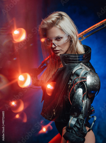 Dressed in black jacket cyber woman from the future poses with her blade in dark blue background.