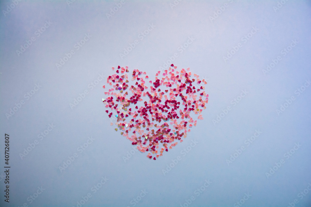 Valentine's day concept. Sparkling pink confetti in shape of heart on blue background. Flat lay style