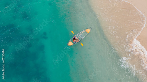 Photography aerial view of blue sea with floating transparent kayak is going into sand beach
