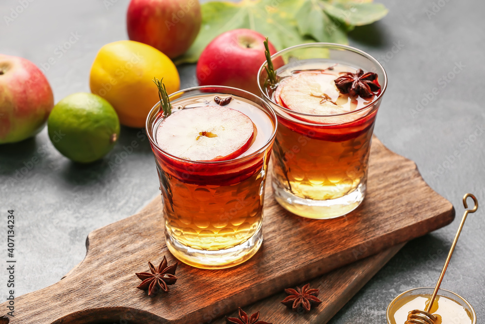 Tasty drink with spices and apple slices in glasses on dark background Tasty drink with spices and apple slices in glasses on dark background