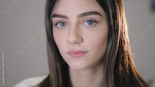 Satisfied blue eyed woman demonstrates stylish permanent makeup on brows posing for camera on light background closeup slow motion