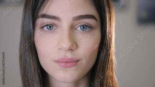 Pleased attractive grey eyed woman demonstrates stylish permanent makeup on brows posing for camera in salon closeup slow motion