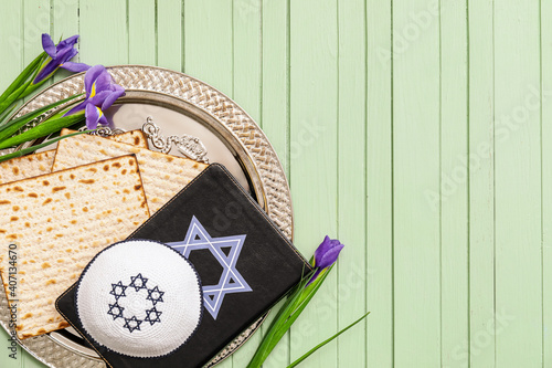 Passover Seder plate with Jewish cap, matzo and Torah on color wooden background photo