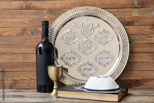 Passover Seder plate with wine, Jewish cap and Torah on wooden background