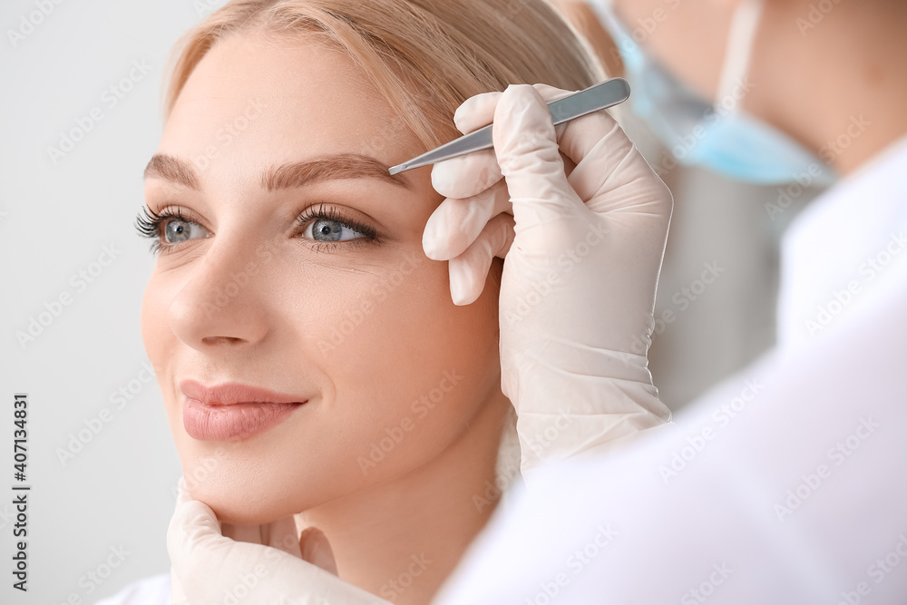 Young woman undergoing eyebrow correction procedure in beauty salon Young woman undergoing eyebrow correction procedure in beauty salon