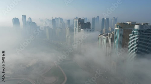 FOG IN UAE: Aerial view of Fog over Sharjah's Khalid Lake, Sharjah skyline covered in the winter morning fog, United Arab Emirates, 4K Drone Footage photo