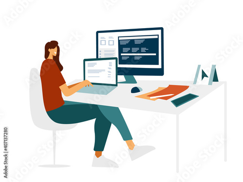 Young beautiful girl programmer behind a laptop and a computer writes a code. Modern flat design, female character IT specialist is typing on the laptop at the work table. Light cozy office.