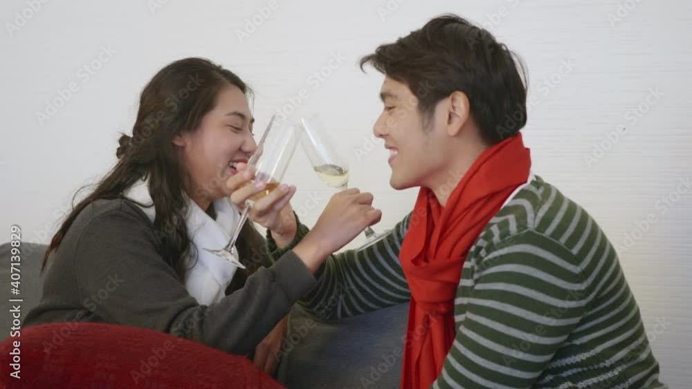 Happy Asian beautiful young family couple husband and wife on sofa in home living room, man and woman sit sofa in love clink glasses with champagne enjoy and drink winter holidays together slow motion Happy Asian beautiful young family couple husband and wife on sofa in home living room, man and woman sit sofa in love clink glasses with champagne enjoy and drink winter holidays together slow motion