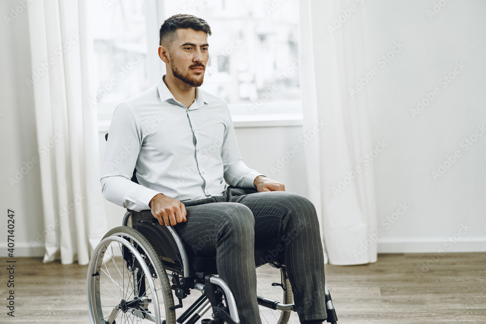 Young disabled man sitting in a wheelchair near the window Young disabled man sitting in a wheelchair near the window