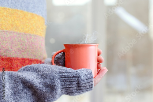 A cup of hot tea in female hands. A hot drink on a winter morning.